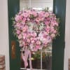 Heart-shaped pink floral wreath on a stand with ribbon