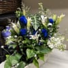 Blue roses and white lilies arranged in a rectangular wooden planter