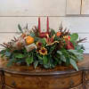 Autumn centerpiece with red candles, orange flowers, and a small pumpkin