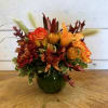 Orange and red floral arrangement in a dark green vase