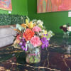 Mixed bouquet in a clear glass vase with pink, orange, purple, and white flowers