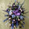 &ldquo;A graceful standing spray showcasing lavender orchids, hydrangeas, delphiniums, and soft pink