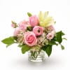 Pink roses and pale yellow lilies in a clear glass vase
