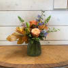 Peach and blue mixed flower arrangement in a green glass vase