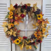 Fall wreath with sunflowers, red flowers, and autumn leaves on a window