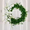 White orchid and greenery wreath on a white easel