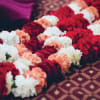 Rows of red, white, and peach flower garlands laid on patterned fabric