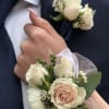 White rose boutonnieres and corsages on a navy suit and wrist