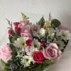 Bouquet of pink roses, carnations, and white daisies wrapped in clear plastic
