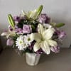 Bouquet of white lilies, lavender roses, and white daisies in a white vase