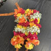 Colorful floral lei made of roses and baby's breath with orange ribbon ties