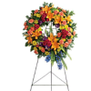Large standing floral wreath on an easel with orange, red, yellow, and blue flowers