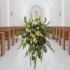 Tall white and green floral arrangement in a church aisle