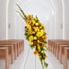 Tall yellow and orange floral spray on a stand in a church aisle