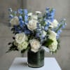 White roses and blue delphinium in a glass vase