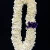 White floral lei with a purple ribbon on a black background