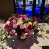 Low centerpiece of pink and lavender roses on a dining table