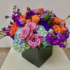 Colorful bouquet of roses, hydrangeas, and purple blooms in a black box
