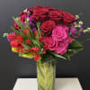 Roses and green in tall glass vase 