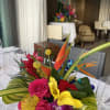Bright tropical centerpiece with orchids, calla lilies, and roses on a dining table