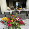 Bright tropical centerpiece with orchids, roses, and bird-of-paradise on a banquet table