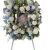 Large floral wreath with white roses and blue flowers around a portrait