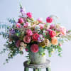 Large mixed bouquet of pink and peach flowers in a textured vase