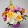 Colorful bouquet of yellow roses, hydrangeas, and mixed blooms in a purple vase