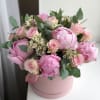Pink peonies and roses arranged in a round pink box