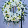 White floral wreath on a wooden easel with roses and orchids