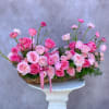 Pink roses and ranunculus arranged in a low basket on a pedestal