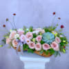 Low floral arrangement of pale pink roses and a blue succulent in a wooden container