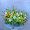 Large mixed floral arrangement in a low bowl with white, yellow, and orange blooms