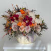 Floral arrangement in a white pumpkin container with roses and orchids