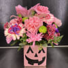 Pink floral arrangement in a jack-o'-lantern vase