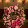 Pink floral wreath on a stand with a bright ribbon bow