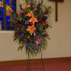 Standing floral spray with lilies, roses, and purple flowers on an easel