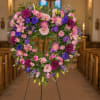 Heart-shaped floral wreath on a stand in pink, purple, and white
