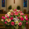 Pink and white floral arrangement with lilies and roses in a church