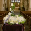 White floral arrangement with blue accents on a draped stand in a church