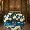 Blue and white floral funeral wreath on a stand in a church