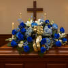 Blue and white floral spray on a casket with a gold ribbon