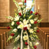 Standing funeral spray with red roses and white lilies on an easel
