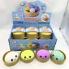 Four colorful squishy toys in round tins with a display box behind them