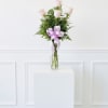 Five pale pink roses in a clear glass vase with a lavender ribbon