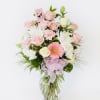 Pink and white mixed flower arrangement in a glass vase with a pink ribbon