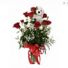 Red roses arranged with a teddy bear in a glass vase