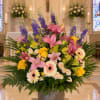 Large mixed floral arrangement in a gray vase with pink lilies and yellow roses