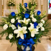 White lilies and blue roses in a vase with a blue ribbon
