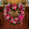 Heart-shaped floral wreath with pink and purple flowers on a stand